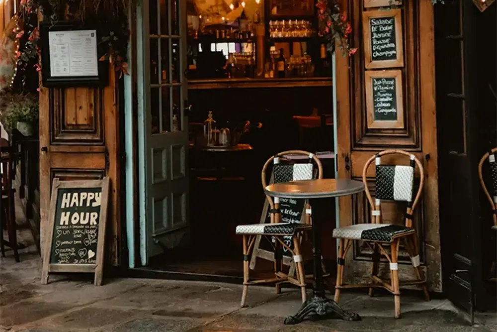 Bistroentré med runt bord och rottingstolar på gatan